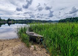 Pochmurne niebo nad jeziorem i łódką w szuwarach