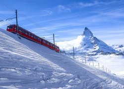 Pociąg na ośnieżonym nasypie z widokiem na szczyt Matterhorn