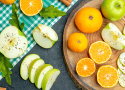Pokrojone jabłka obok pomarańczy na desce