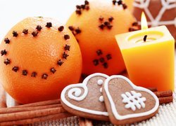 Pomarańcze i pierniki położone obok świecy