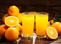 Pomarańcze obok szklanek z sokiem
