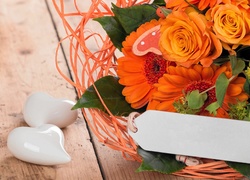 Pomarańczowy bukiet kwiatów i białe serduszka obok
