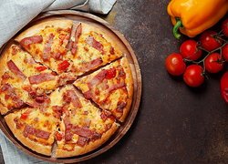 Pomidory i papryki obok pizzy z boczkiem