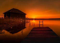 Pomost i dom nad jeziorem o zachodzie słońca