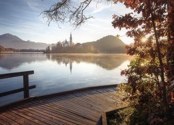 Słowenia, Jezioro Bled, Wyspa Blejski Otok, Kościół Zwiastowania Marii Panny, Góry Alpy Julijskie, Wschód Słońca, Pomost, Promienie słońca, Drzewa