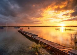 Pomost i żaglówki na jeziorze o wschodzie słońca