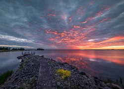 Pomost na skalnym cyplu nad jeziorem na tle kolorowego nieba