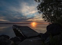 Pomost nad jeziorem na tle zachodzącego słońca