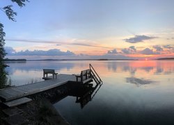 Pomost z ławkami nad jeziorem o zachodzie słońca