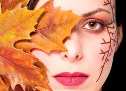 Portret kobiety z okiem zakrytym jesiennym liściem