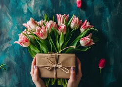 Prezent w dłoniach i bukiet tulipanów