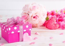 Prezent w różowym pudełku obok serduszek i kwiatów