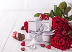 Prezent z czekoladkami obok róż