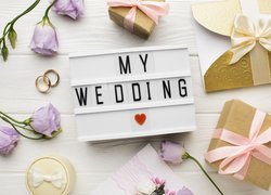 Prezenty i obrączki obok ramki z napisem My Wedding