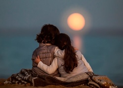 Przytulone dzieci obserwują zachód słońca