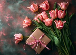 Pudełko z prezentem obok różowych tulipanów
