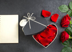 Róże obok pudełka w kształcie serca i notatnika