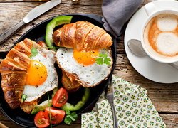 Rogaliki i jajka sadzone obok filiżanki kawy