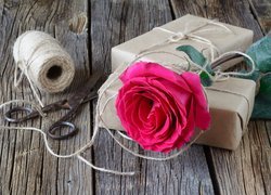 Róża na prezentach obok szpulki i nożyczek