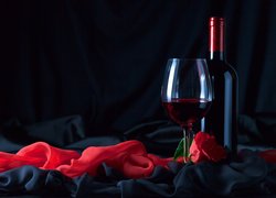 Róża obok butelki i kieliszka z winem