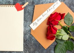 Róże na kopercie z listem miłosnym obok notesu