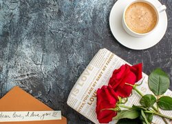 Róże na prezencie obok filiżanki kawy i listu miłosnego