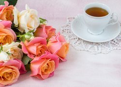 Róże obok filiżanki herbaty