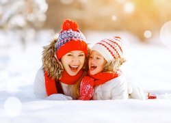 Roześmiana kobieta z dziewczynką na śniegu