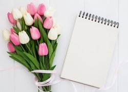 Różowe i białe tulipany obok notesu