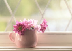 Różowe kwiaty w wazoniku na parapecie okna
