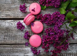 Różowe makaroniki i gałązki fioletowego bzu na deskach