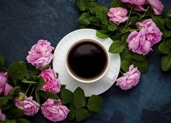 Różowe róże obok filiżanki z kawą