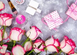 Różowo-białe róże obok kosmetyków i prezentów