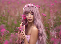 Różowowłosa kobieta w kwiatach na rozmytym tle