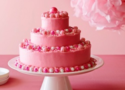 Różowy trzypiętrowy tort ozdobiony kuleczkami