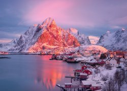 Rozświetlone słońcem ośnieżone góry i wioska Reine na norweskich Lofotach