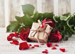 Rozsypane płatki obok róż i prezentu