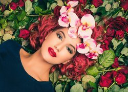 Rudowłosa kobieta w wianku leżąca na różach