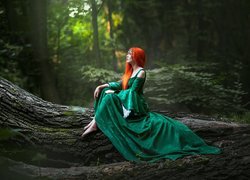 Rudowłosa kobieta w zielonej sukni na konarze drzewa
