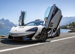 Samochód McLaren 57OS prezentuje się na drodze z widokiem na góry