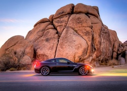 Samochód Nissan GT-R Track Edition z włączonymi światłami na tle skały