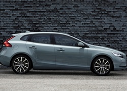 Samochód Volvo V40 z roku 2017 stoi przy ceglanym murze