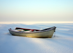 Samotna łódka na zamarzniętym jeziorze
