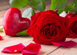 Serce obok czerwonej róży i rozsypanych płatków