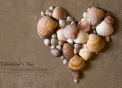 Serce ułożone z muszelek na piasku z życzeniami walentynkowymi
