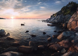 Skały i kamienie nad brzegiem morza w blasku wschodzącego słońca