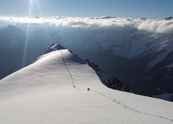 Ślady alpinistów na ośnieżonym górskim szczycie