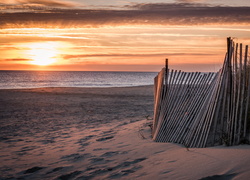 Słońce wschodzi nad morską plażą