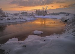 Śnieg na brzegach rzeki o wschodzie słońca