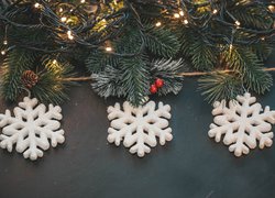 Śnieżynki na oświetlonych lampkami gałązkach choinki